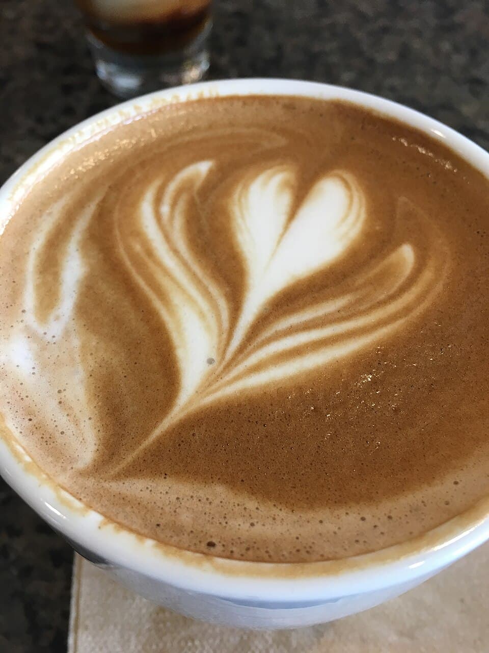A café latte with a poured milk-foam heart on espresso crema.